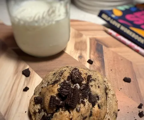 Cookies and cream cookie topped with chocolate cookie pieces beside a jar of milk